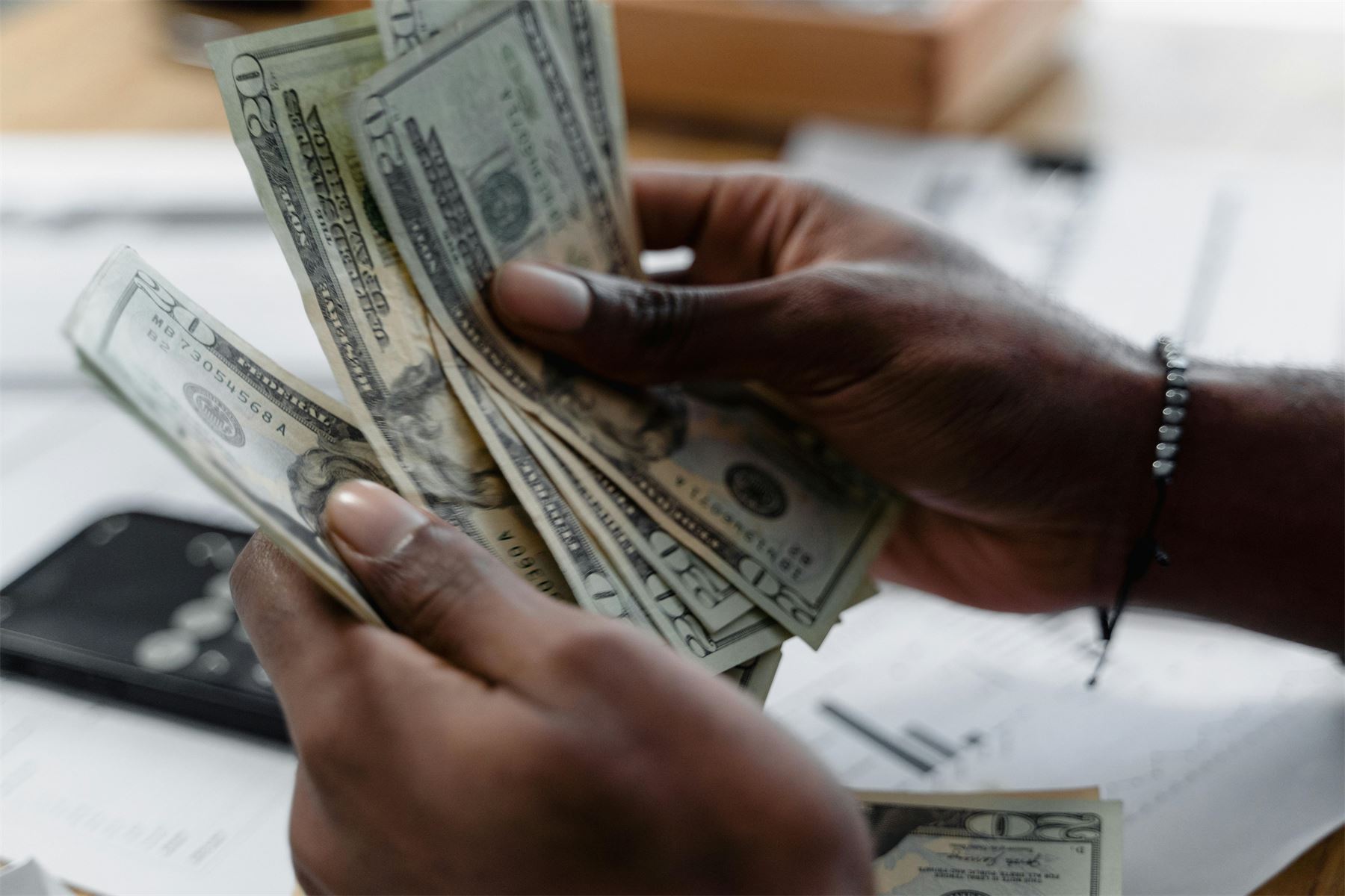 Manos contando billetes sobre una mesa