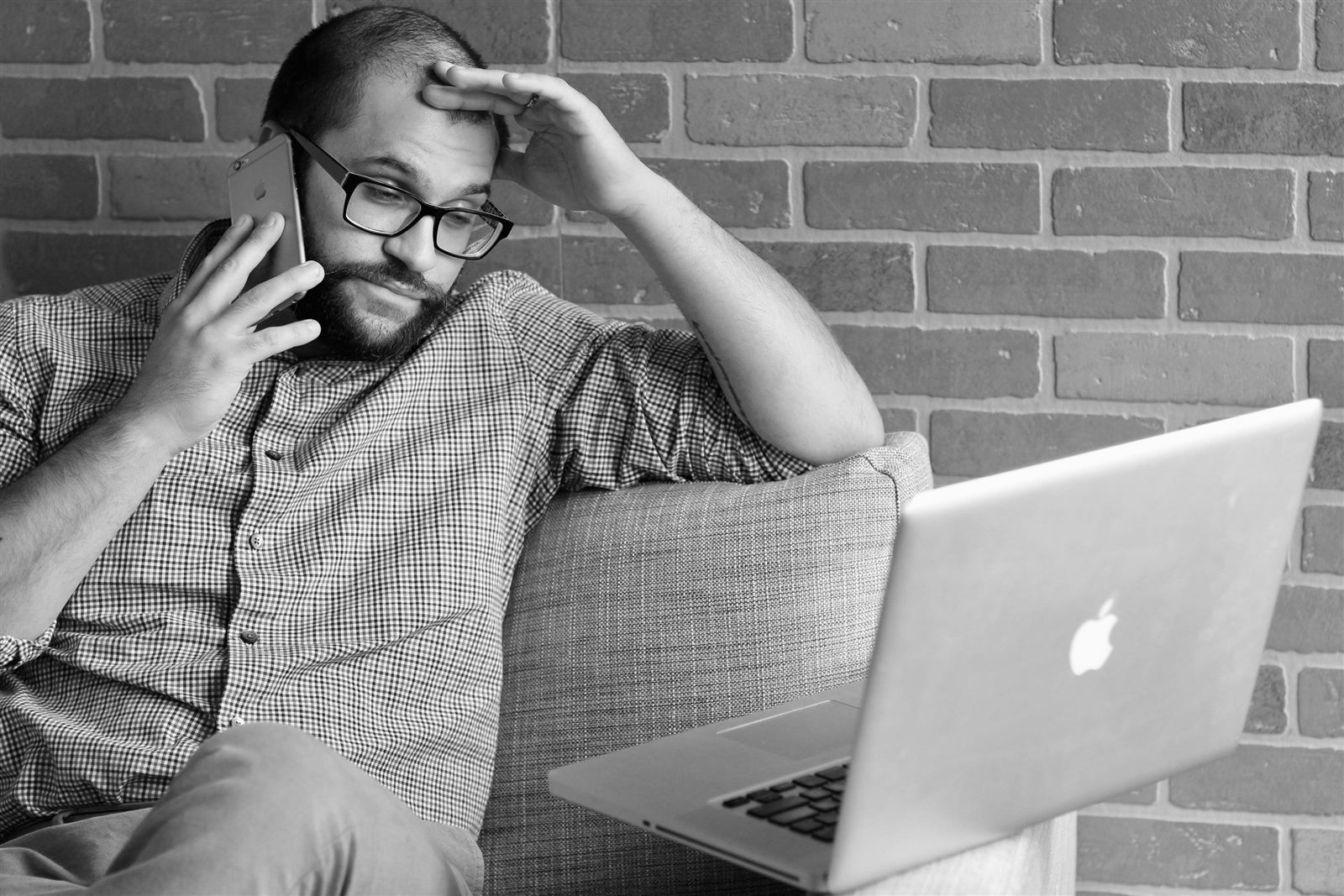 Hombre preocupado usando el teléfono frente a una computadora